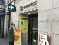 Ángel fuma en la puerta de su Carrefour Express, en la Plaza del Ángel de Madrid.