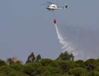 Un helicóptero de extinción de incendios trabaja en el Paraje de Fuente de la Corcha, en el término municipal de Beas (Huelva). /EFE
