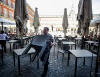 Varios empleados de un bar de la Plaza Mayor de Madrid recogen la terraza un día antes de que se cierre toda la hostelería para frenar contagios por coronavirus, en Madrid
