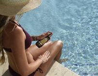 Una joven en una piscina se aplica protección solar sobre la pierna