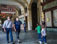Personas con mascarillas caminan bajo las arcadas de la Piazza San Carlo durante la fase 2 de la emergencia del coronavirus, en Turín, Italia. /EFE