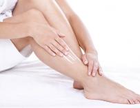 Una mujer se aplica crema hidratante en las piernas