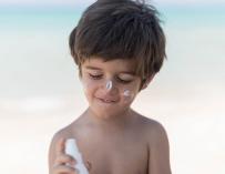 Un niño se aplica crema solar en la cara