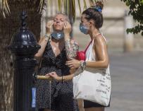 Dos turistas internacionales se refrescan en una fuente de Sevilla durante el mes de agosto.