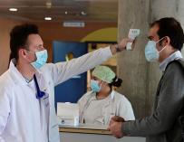 Un sanitario toma la temperatura a un hombre que accede al Hospital de Alcorcón en Madrid.