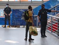Un agente de la Policía Nacional da indicaciones a un pasajero mientras vigilan la Estación de Atocha Renfe, en Madrid