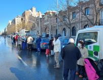 Varias personas hacen cola en la calle Santa Engracia de Madrid, que se encuentra despejada de la nieve gracias a los esparcidores de sal y salmuera que se están distribuyendo en la capital.