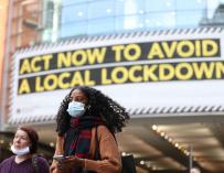 20 October 2020, England, Manchester: A woman wears a face mask walks past by a sign rgarding the upcoming lockdown in Manchester. Greater Manchester will be placed under stricter coronavirus controls after last-ditch talks with the UK Prime Minister Boris Johnson aimed at securing additional financial support concluded without an agreement. Photo: Martin Rickett/PA Wire/dpa (Foto de ARCHIVO) 20/10/2020 ONLY FOR USE IN SPAIN