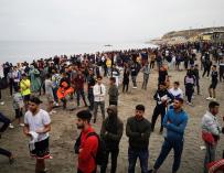 Cientos de personas esperan en la playa de la localidad de Fnideq (Castillejos) para cruzar los espigones de Ceuta este martes en una avalancha de inmigrantes sin precedentes en España.