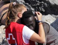 Una cooperante de Cruz roja abraza a un migrante recién llegado a Ceuta