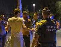 Un agente de la Guardia Urbana desaloja a jóvenes de la playa de la Barceloneta tras la entrada en vigor del toque de queda en Cataluña.
