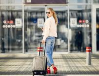 Una joven camina con su maleta dirección al aeropuerto