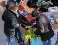 Personas en riesgo de exclusión acuden a recoger alimentos, en la plaza de San Amaro, a 7 de enero de 2022, en Madrid (España).