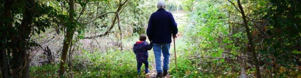 Fotografía de un abuelo jubilado paseando junto a su nieto.