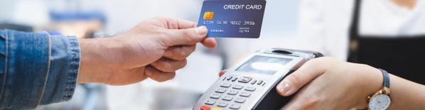 Una persona pagando con tarjeta de crédito en un datafono de un comercio