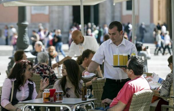 Un camarero sirve bebidas en una terraza en la plaza de la Virgen de Valencia. (EFE)