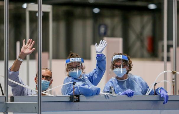 Dos sanitarias protegidas con mascarilla, guantes y pantalla protectora y un paciente saludan