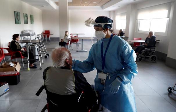 Una sanitaria atiende a un anciano alojado en una residencia en el barrio madrileño de Villaverde, mientras se procede a la desinfección de las instalaciones para evitar la propagación del coronavirus.