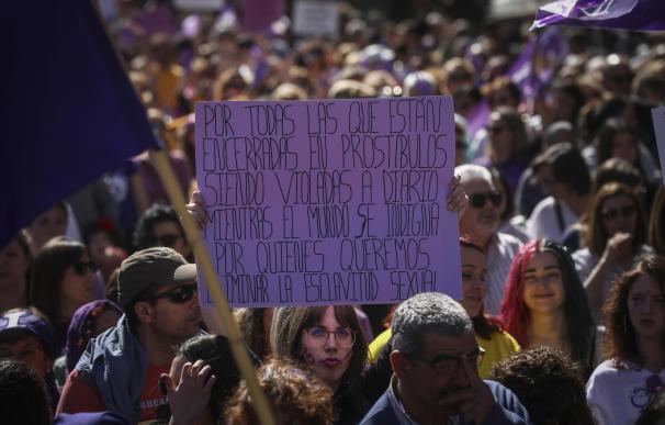 Una mujer sostiene su pancarta con un mensaje de protesta en contra de la prostitución durante la manifestación por el Día Internacional de la Mujer en Sevilla
