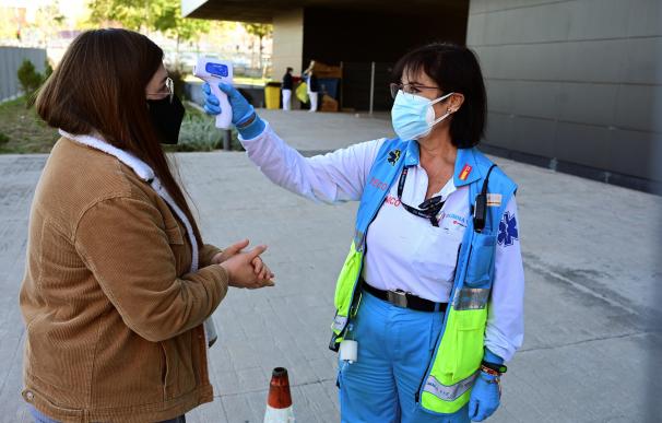 Una trabajadora toma la temperatura a una vecina antes de someterse a un test de antígenos en el Centro Cultural Lope de Vega, en Vallecas