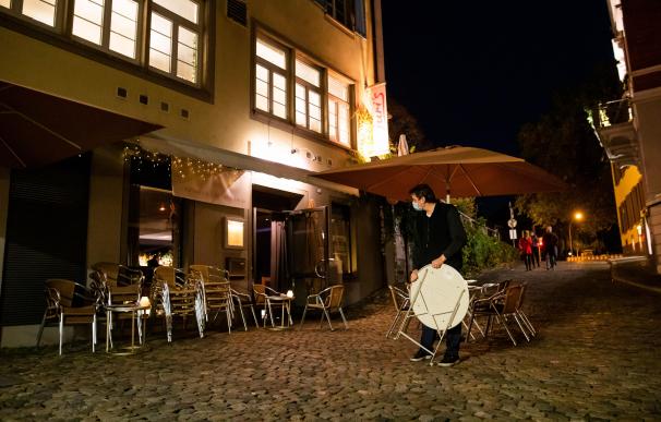 Un trabajador de un bar alemán recoge la terraza a mediados de esta semana tras las nuevas medidas.