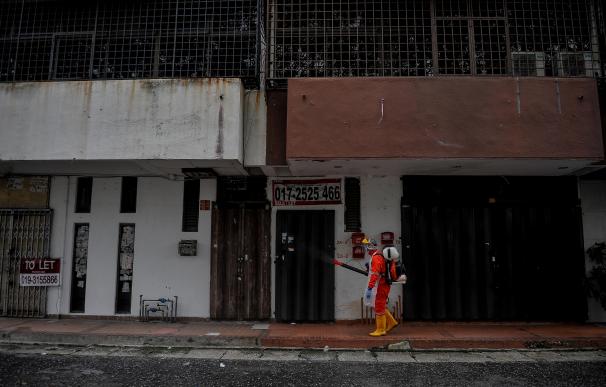 Un empleado sanitario desinfecta la calle y varios edificios en Malasia.