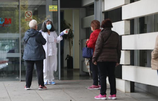 Una trabajadora sanitaria habla con varias pacientes que esperan en la puerta del Centro de Salud Doctor Tamames, en la zona básica de salud de Doctor Mamames, en Coslada, Madrid (España)