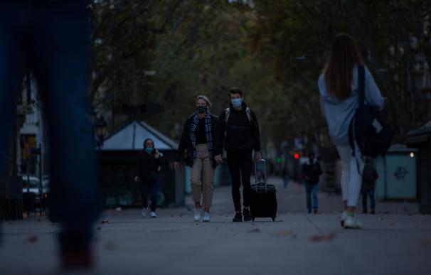 Dos jóvenes caminan por una calle de Barcelona poco antes del toque de queda.