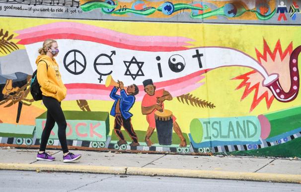 Una estudiante con mascarilla pasea frente a un mural en Rock Island, en Estados Unidos