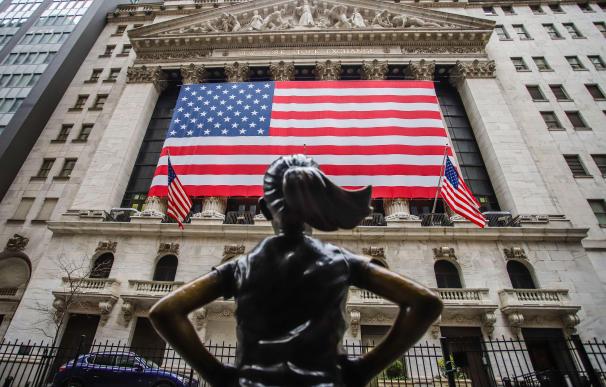 Fachada del New York Stock Exchange adornada con una bandera gigante de Estados Unidos.