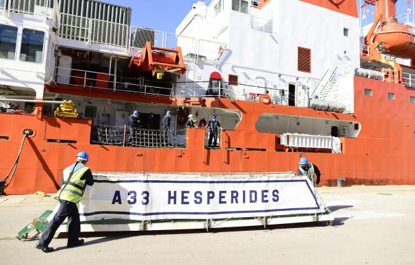 Dos operarios colocan un cartel del Buque de Investigación Oceanográfica (BIO) 'Hespérides' durante el momento de atracar en el puerto de Cartagena, Murcia (España)