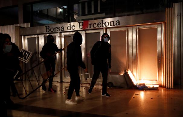 Varios manifestantes queman un contenedor en la puerta de la Bolsa de Barcelona.