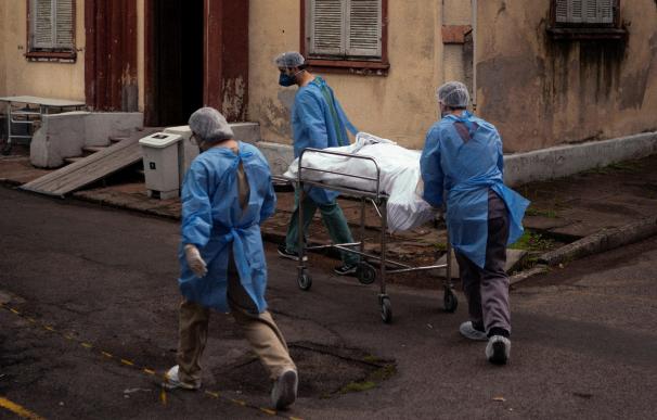 Enfermeros trasladan el cuerpo de un fallecido a una morgue improvisada en la iglesia del hospital Centenario.