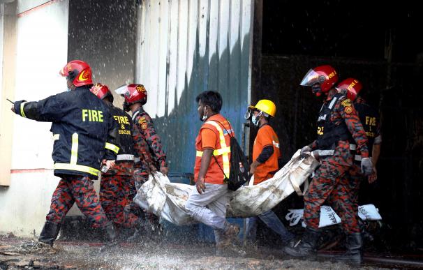 Los bomberos retiran a una víctima del incendio en una fábrica que ha dejado al menos 52 muertos.
