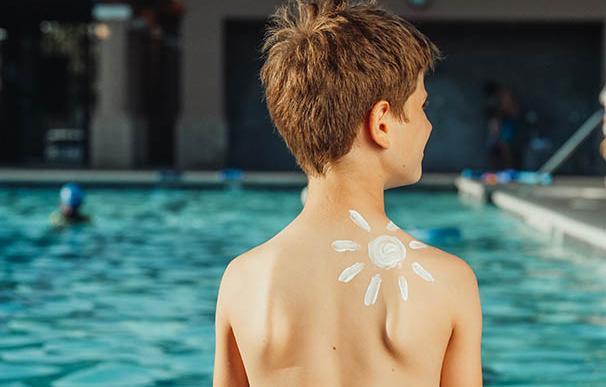 Niño en la piscina con crema solar