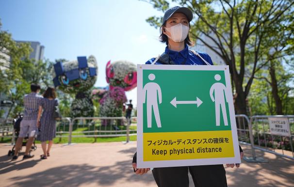Una empleada con un cartel que pide mantener la distancia física para evitar el contagio de Covid en Tokio, Japón.