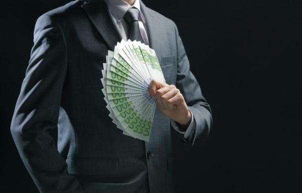 Un hombre con éxito en los negocios portando un fajo de billetes.