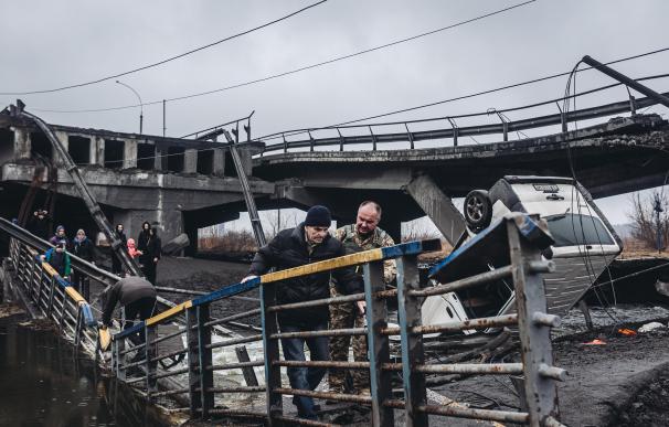 Un hombre mayor cruza el río tras el bombardeo de un puente en Irpin