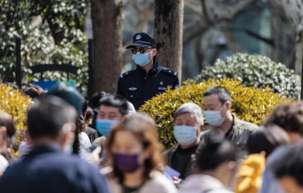 Un oficial de policía supervisa a las personas que hacen cola para las pruebas masivas de COVID-19 en un parque público, en Shanghái, China.