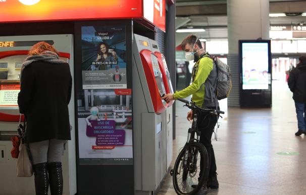 Un viajero con bicicleta adquiere un billete en un dispensador en la estación de Atocha.