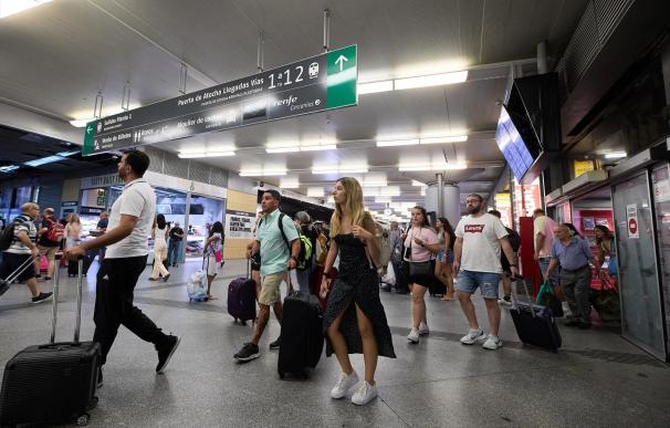 Un grupo de personas con maletas camina por uno de los pasillos de la estación de Atocha-Almudena Grandes
