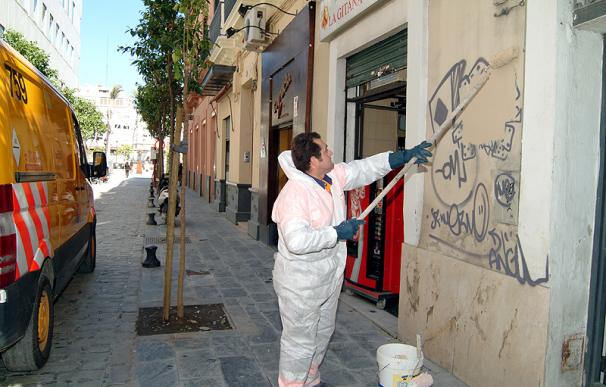 Un empleado del Ayuntamiento de Sevilla elimina pintadas en una fachada.