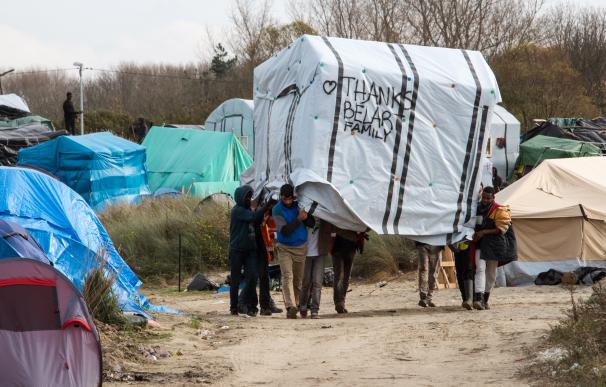 Migrantes trasladan una tienda de campaña en el "New Jungle", campamento de inmigrantes de Calais