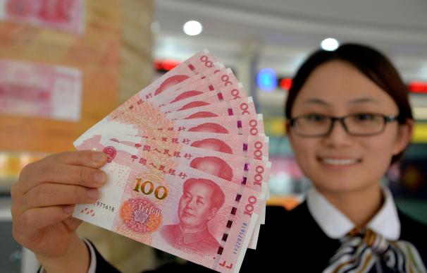 A bank employee shows new 100-yuan banknotes in Ha