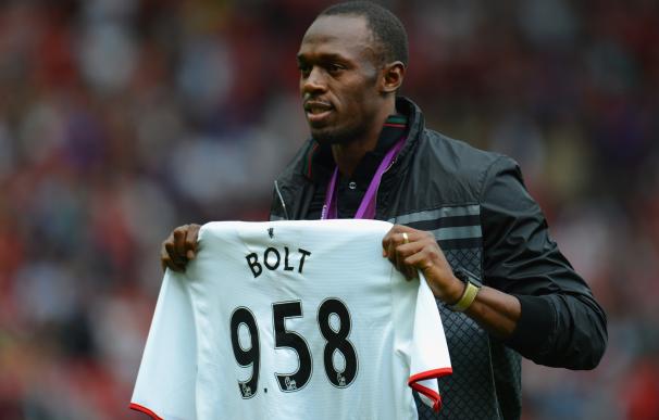 Bolt posa con una camiseta del United y su récord del mundo.
