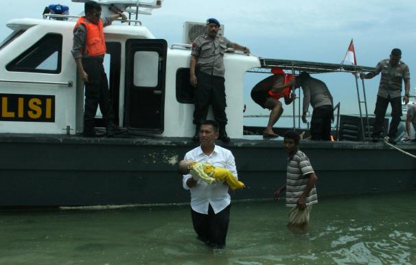 Un policía lleva un bebé ahogado tras el naufragio / AFP