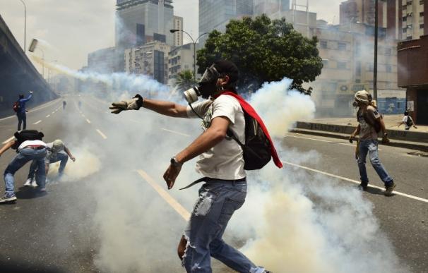 Manifestantes lanzan de vuelta a la Policía botes de gases lacrimógenos en Caracas el 19 de abril de 2017 (Ronaldo SCHEMIDT / AFP)