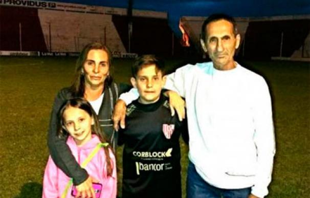 El niño argentino posa con su familia en el campo de su equipo de fútbol
