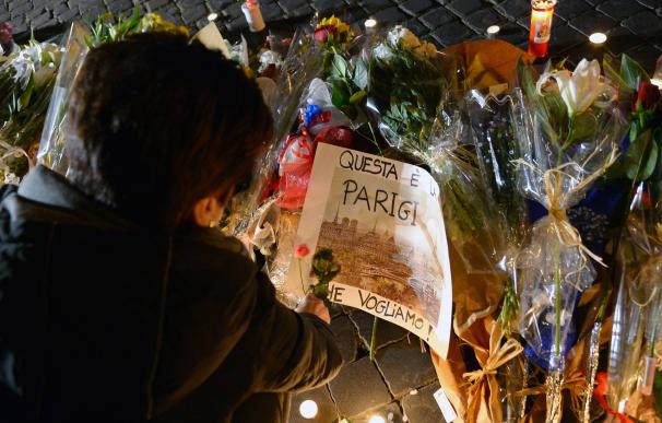 A woman lays flowers near a note picturing Paris a