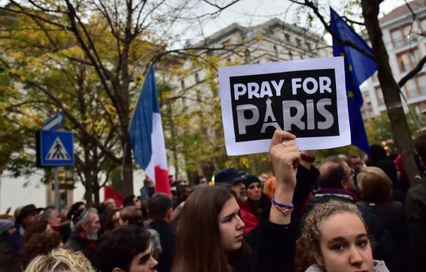 A woman holds a placard reading "Pray for Paris" i